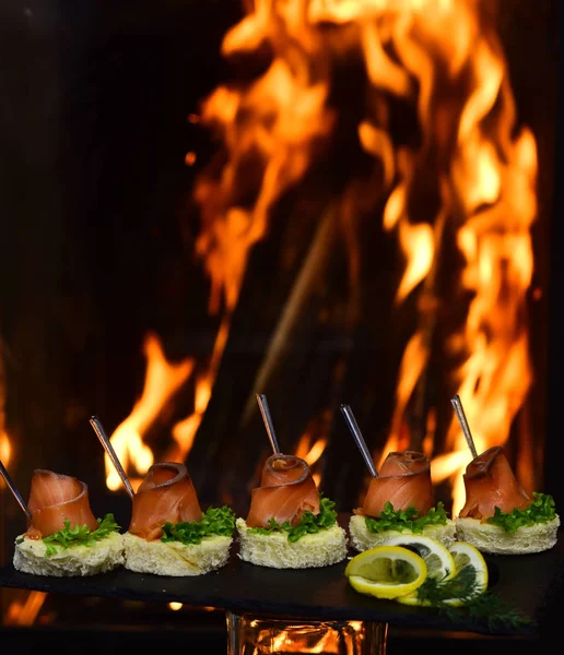 Toast met zalm op het branden van de vlam achtergrond. Gezond ontbijt met volkorenbrood toast met roodbaars op leisteen. Geur van vis — Stockfoto