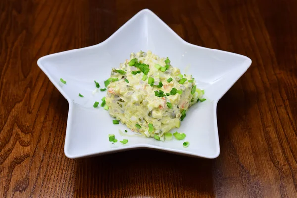 Traditional Russian salad in star shaped bowl. Serving russian salad or olivier with mayonnaise on wooden table. The future of tradition