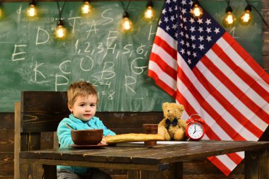 küçük bir erkek öğrenci çocuğun yanında Amerika bayrağı.
