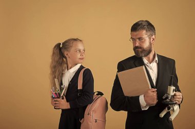 Çocuk ve öğretmen kitap ve mikroskop tutun. Kız çantası ile