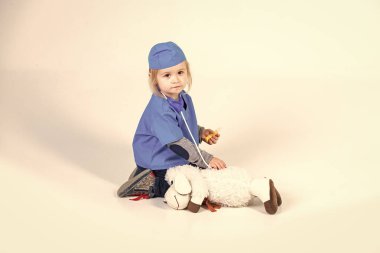 Doktor veteriner oyuncak hayvan ile oynarken üniforma içinde küçük çocuk