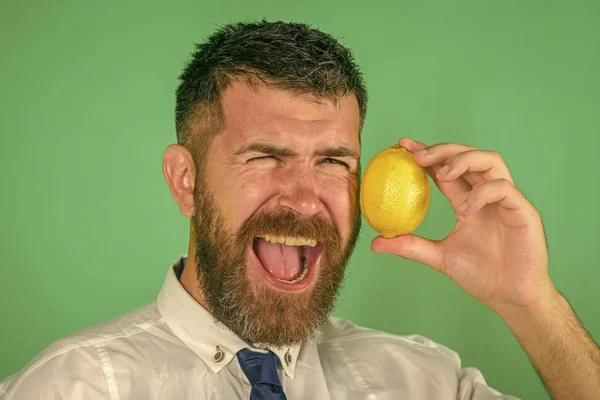 Ευτυχισμένος άνθρωπος με γένια τρώνε φρούτα λεμόνι σε πράσινο φόντο — Φωτογραφία Αρχείου