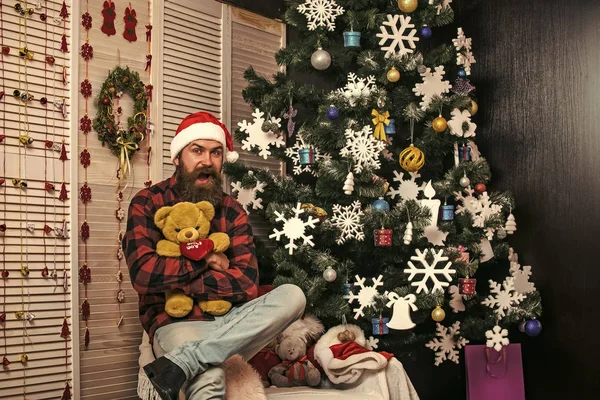 Nieuwjaar man in hat zitten bij de kerstboom. — Stockfoto