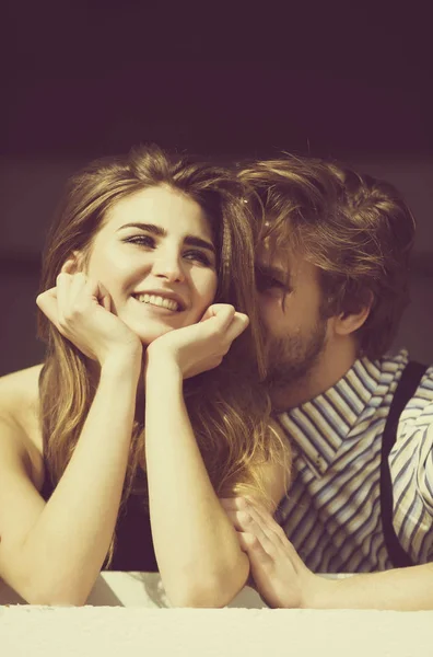 Hombre guapo susurrando al oído a una chica bonita sonriente —  Fotos de Stock