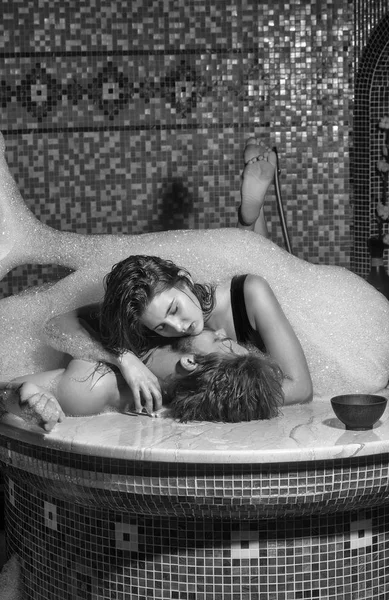 Muskulöser Mann und sexy Frau liegen in der Badewanne mit Schaum — Stockfoto