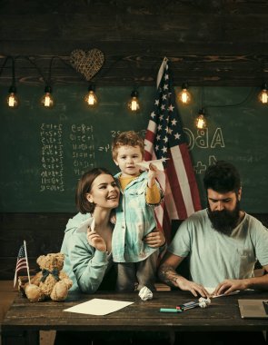 Resepsiyon ile kağıt uçak yapma evlat, Amerikan ailesi. Anne oğlu Amerikan gelenekleri oynarken öğretim. Ebeveynler sınıf ABD bayrağı ile kara tahta arka plan ile evlat. Evde eğitim kavramı.