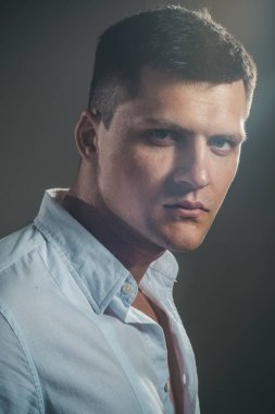 Moda genç ciddi adam kameraya gri arka plan üzerinde seyir gömlekli