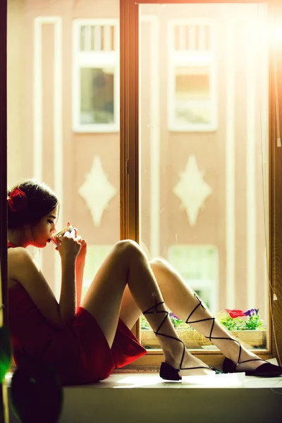 Dziewczyna w czerwonej sukience pić herbatę z kubka — Zdjęcie stockowe