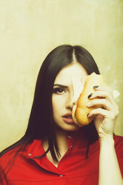 Сексуальная красивая брюнетка серьезная женщина ест большой сэндвич или бургер — стоковое фото