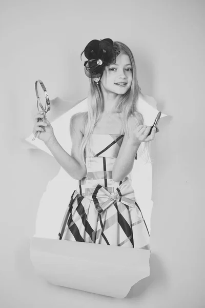 A menina no estilo de alfinete em um vestido de vestir, olha em um espelho de bolso — Fotografia de Stock