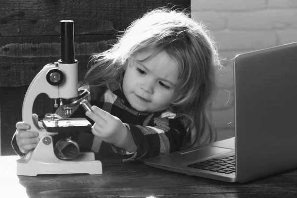 Estudante menino com laptop e microscópio estudo no local de trabalho educacional — Fotografia de Stock