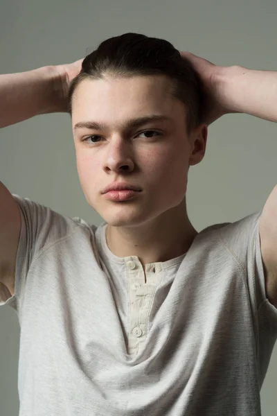 Guy sur le visage confiant en chemise légère touche les cheveux, fond gris. Macho avec coupe de cheveux longue élégante. Concept coiffeur et coiffure. Homme à la peau lisse sur le visage regardant la caméra . — Photo