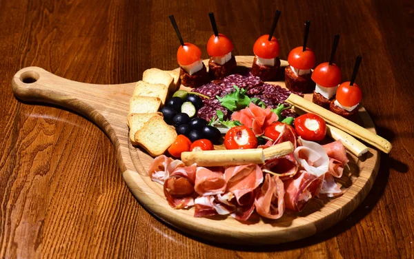 Bandeja antipasto. Placa de carne fría con palitos de pan grissini sobre fondo de madera, concepto antipasto. Servimos pasión —  Fotos de Stock