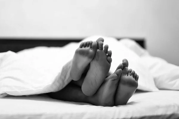 male and female feet in bed