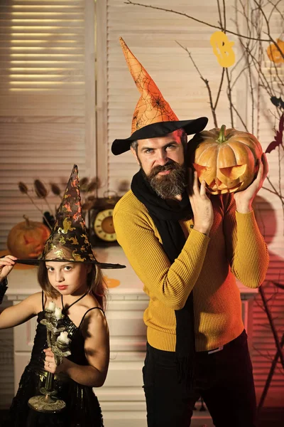 Tata i dziecko w kapelusze czarownice posiadają dyni i żyrandol. — Zdjęcie stockowe