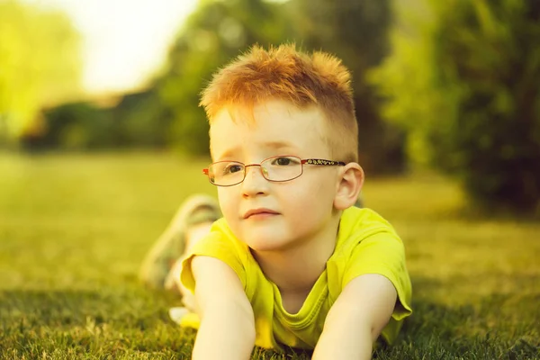 Junge mit roten Haaren in Brille im Gras — Stockfoto