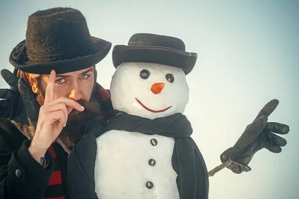 Snowman and man in gentlemen hats and scarves