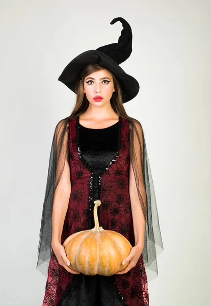 Halloween Witch with a carved Pumpkin. Halloween holiday concept. Holiday halloween with funny carnival costumes on a halloween background