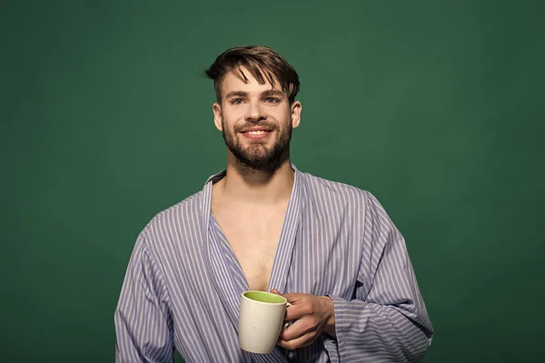 Счастливый человек с чашкой на зеленом фоне — стоковое фото