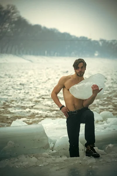 Man met gespierde blote borst houden gebarsten ijsblok, winter — Stockfoto