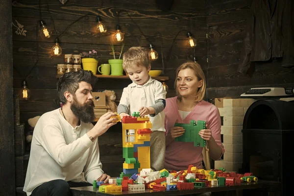 教育游戏的概念。父母和他们的儿子玩塑料积木。妈妈帮助她的儿子和丈夫用五颜六色的砖头建造一座塔 — 图库照片