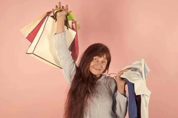 Woman with long red hair hold colorful shopping bag.