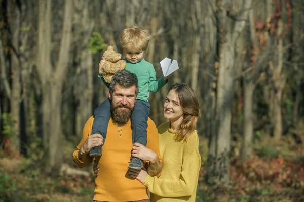 Famiglia felice su passeggiata di piacere in parco. Famiglia felice di padre e madre con piccolo figlio sorridere all'aperto. Rilassarsi sulla natura — Foto Stock