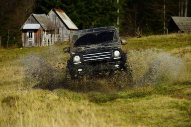 Su birikintisi geçiş ve sıçrama yapma Suv. Yoldan araba siyah renkli bölümü yarış alır. Aşırı ve dört tekerlekli sürücü kavram. Ülke toplanma veya Ralli RAID kırsal kulübe bir yana forest yakınındaki çapraz