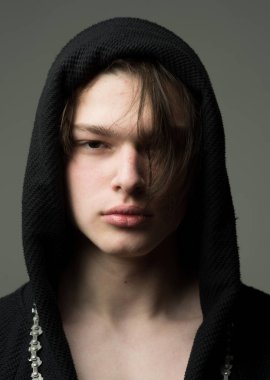 Siyah hood, gri arka planda emin yüz adam. Maço siyah bornoz ile kukuleta, yakın çekim. Erkeklik kavramı. Pürüzsüz cilt yüz ve boyun kameraya bakarak üzerinde olan adam.