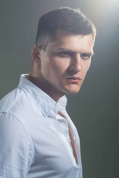 Jovem homem sério em camisa branca sobre fundo cinza. Retrato de estúdio — Fotografia de Stock