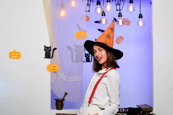 Halloween Witch with in magic hat. Beautiful young surprised woman in witches hat and costume. Happy young women in witch halloween costumes on party smiling