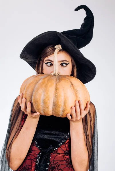 Expresión de cara graciosa. Gente loca. Mujer posando con Calabaza. Hermosa joven sorprendida mujer en sombrero de brujas y traje celebración de calabaza . — Foto de Stock