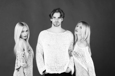 İkiz kız kardeşler, güzel kızlar, kadınlar veya şık modelleri ile uzun, sarı saç, makyaj ve yakışıklı adam veya şık, örme kazak yeşil zemin üzerine poz maço. Moda. Aile ve dostluk