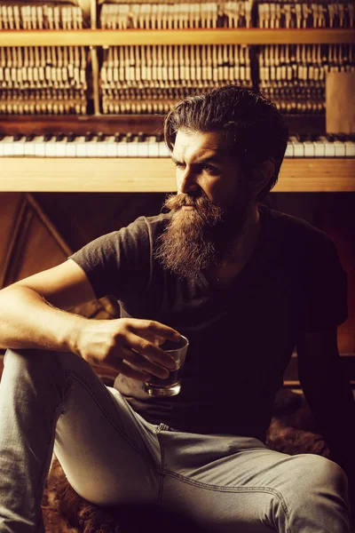 Homme barbu avec verre près du piano en bois — Photo