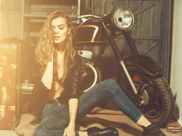 Красивая байкерша стоит с винтажным чемоданом на мотоцикле — стоковое фото