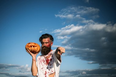 Cadılar Bayramı adam işaret parmağı ile bulutlu mavi gökyüzü üzerinde kabak