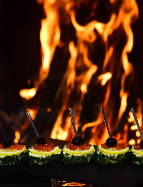 Tasty red caviar snacks on burning fire. Caviar snacks with lemon on slate. Paradise on your plate — Stock Photo, Image