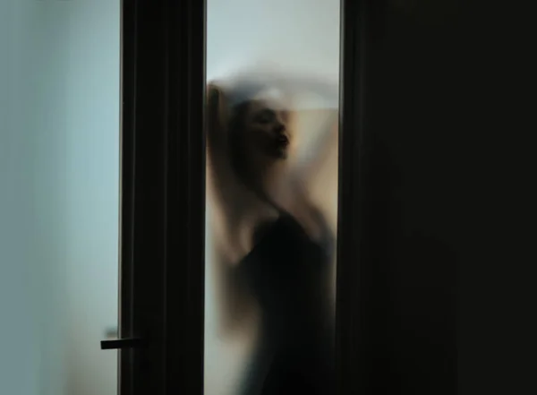 Woman behind blurry glass. Defocused blurry image — Stock Photo, Image