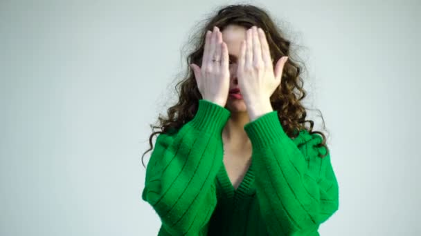 Kudrnatá dívka v zeleném svetru s rovnátkama ukončí její tvář rukama a ukazuje různé emoce. Pařížanky v zimní oblečení. Módní vzhled a krásu koncept.