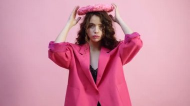 Kaşlı ayraçlar içinde pembe bir ceket kızla hava öpücük onun elinde bir kalp ile pembe bir arka plan üzerinde yapar. Sevgililer günü kavramı. Pembe arka plan izole.