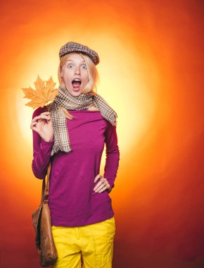 Güzel kız boşaltmak için tahta arka plan ile. Turuncu zemin üzerine altın varak tutan kadın. Moda kızlar. Kız mal ve hizmetlerin tanıtır. Sürpriz kadın.