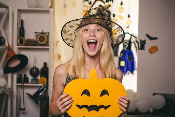 Mujer bella posando con calabaza y sombrero de Halloween. Hermosa joven sorprendida mujer en sombrero de brujas y traje señalando la mano - mostrando productos . — Foto de Stock