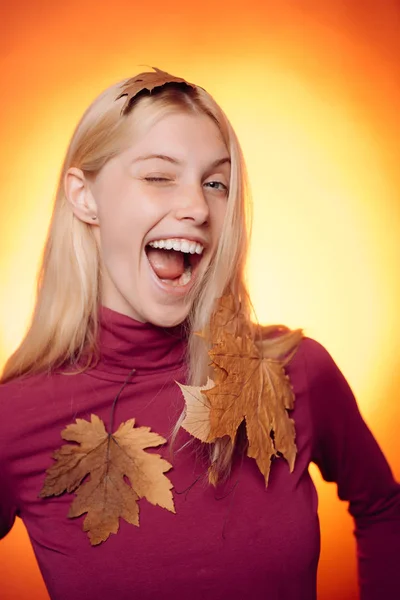 Gyönyörű érzéki szőke játszik a levelek. Boldog fiatal nő őszre készül. Meglepett asszony gazdaság levél. Közeli kép: portré. Őszi koncepció. Vicces kifejezés arcát. Őrült emberek. — Stock Fotó