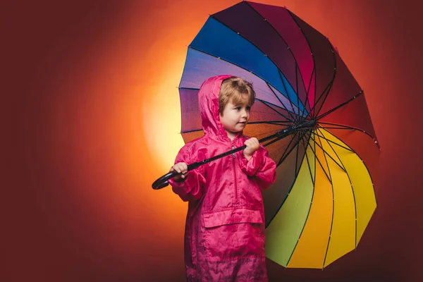 Menino bonito está se preparando para o dia de chuva de outono. Menino alegre em capa de chuva com guarda-chuva colorido. Miúdo à chuva. Venda para toda a coleção de crianças do outono, descontos incríveis e escolha maravilhosa . — Fotografia de Stock