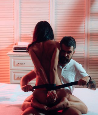 Seksi Dirty Talk gece zamanında. Seksi çift yatakta. Esaret ve bdsm kavramı. Sarılı elleri - memnuniyeti. Tutkulu çıplak kadın ve erkek iç çamaşırı pantolon içinde. Cinsel Harassing kadın. Baskın erkek.