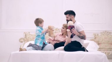 Çocuk ve ailesi yatakta yatmak ve yumuşak oyuncaklar ile oynamak. Mutlu bir aile kavramı. Mutlu aile yatakta iletişim kurar..