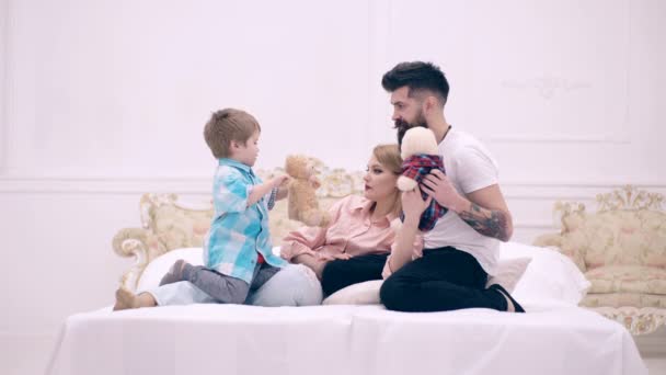 Il ragazzo e i suoi genitori si sdraiano a letto e giocano con giocattoli morbidi. Il concetto di famiglia felice. Felice famiglia comunica a letto . — Video Stock