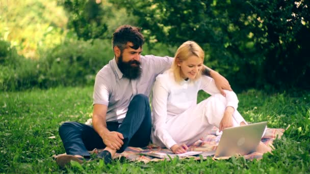 The girl and her boyfriend are sitting on a blanket in the park and chatting. A boy hugs a girl sitting on a blanket in a park. — Stock Video