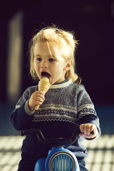 Bambino o piccolo ragazzo mangiare gelato su moto giocattolo — Foto Stock