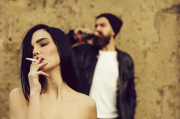 Menina fumar cigarro e homem borrado hipster bebida de garrafa — Fotografia de Stock